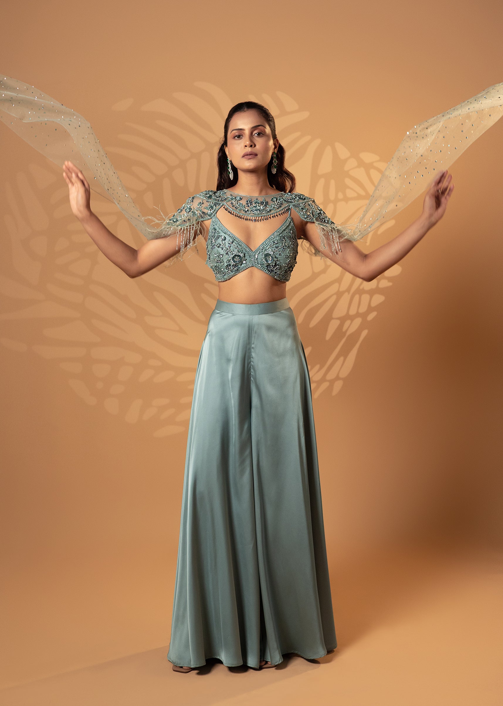 Woman wearing a green embroidered top and skirt against a beige background